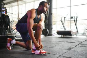 Sportsman tying shoelaces, ready for workout in gym, free space photo