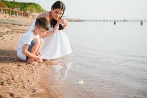 mother and son walking on sunset beach photo