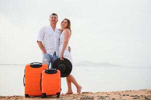 Young couple with suitcase on the beach in summer day. The concept of recreation at sea and travel photo