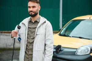 hombre cargando eléctrico coche por el trabajo foto