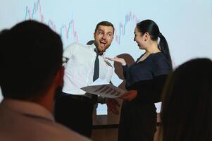 Trading teaching. Male leader talking to employees, showing the plan on the projector in office of stock exchange company. photo