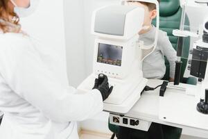 Modern medical equipment. Close up of ophthalmologist using auto refractometer while examining child eyes. photo