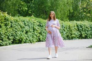 The pregnant girl on walk in city park photo