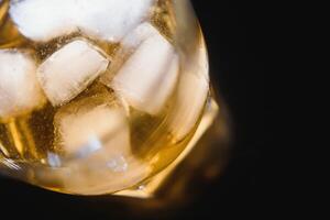 Glass of scotch whiskey and ice over black background photo