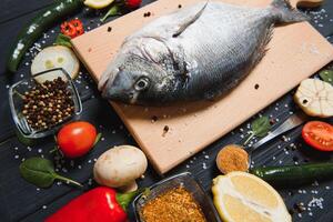 Raw fish cooking and ingredients. Dorado, lemon, herbs and spices. Top view with copy space on table photo