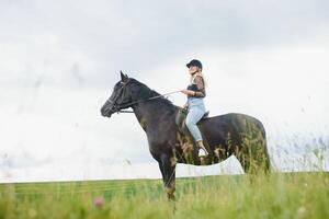 Young woman riding a horse on the green field photo