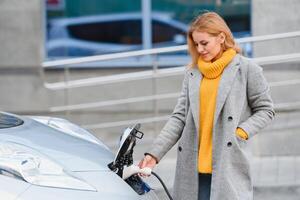 Woman near a rental electric car. Vehicle charged at the charging station. photo