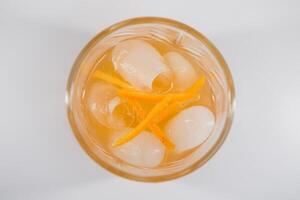 Glass of Boulevardier cocktail with big ice cube and orange zest, classic cocktail Boozy Boulevardier with Orange and Vermouth isolated on white background photo