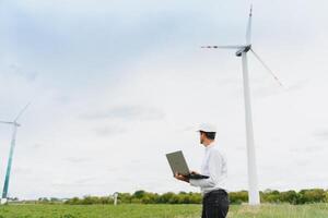 ingeniero trabajador con ordenador portátil o computadora a viento turbina poder estación construcción sitio, copiar espacio. foto