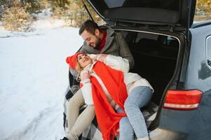 sonriente juntos. bonito Pareja tener fin de semana a campo a invierno tiempo. sentado en el posterior parte de moderno coche. foto