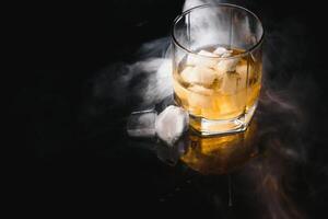 Glass of the whiskey with ice and a decanter isolated on a black background photo