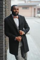 Fashion portrait of a handsome young African American business man walking outdoors in a casual pose. photo