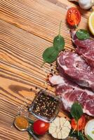 Raw pork meat on wooden cutting board at kitchen table for cooking pork steak roasted or grilled with ingredients herb and spices , Fresh pork. photo