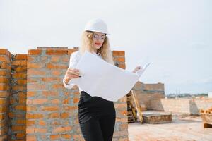 hermoso mujer ingeniero es revisando el planes de un construcción trabajo foto