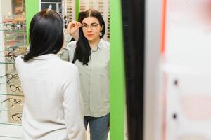 woman trying on optical glasses in eyewear store. photo