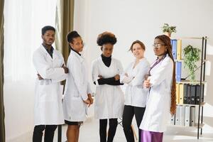 multirracial equipo de doctores en un hospital en pie en un corredor Listo a hacer un sala redondo. foto