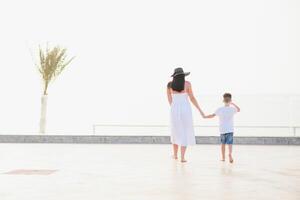 contento familia madre y hijo en el playa por el mar en verano foto