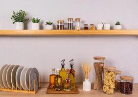 an open kitchen shelf and part of a wooden kitchen countertop with a set of containers for storing food and a dryer with plates. Front view. photo