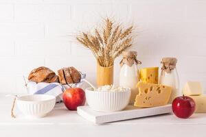 A fresh dairy products, sour cream, cheese, milk ,bread, apples and ears of corn in a vase for the holiday of Jewish Shavuot. Front view. photo