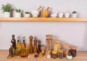 Stylish kitchen background with a set of bottles with various cooking oils, glass jars with spices. Front view of an open wooden shelf photo