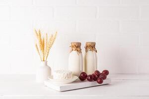 Fresh dairy products on a white wooden board and a vase with ears of corn on a wooden table. Concept of the Jewish holiday of Shavuot. Eco style photo