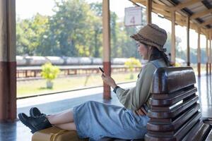 Young woman holding mobile in a train station. Commuting to work. Public transport concept photo