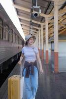 Young woman with suitcase waits at the metro station while the train arrrives, Tourism and travel in the summer. Vacations for the student. Work and travel photo