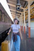 Young woman with suitcase waits at the metro station while the train arrrives, Tourism and travel in the summer. Vacations for the student. Work and travel photo