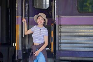 joven mujer con maleta murga a el metro estación mientras el tren llega, turismo y viaje en el verano. vacaciones para el alumno. trabajo y viaje foto