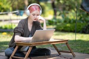 Woman working at the laptop in the backyard with a lot of greenery,  laptop and portrait of woman in park for education photo