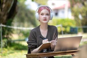 Woman working at the laptop in the backyard with a lot of greenery,  laptop and portrait of woman in park for education photo