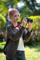 hermosa joven artista mujer tomando foto en flores jardín. joven linda niña llevar el cámara en el jardín