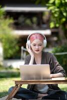 Woman working at the laptop in the backyard with a lot of greenery,  laptop and portrait of woman in park for education photo