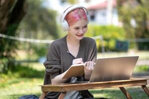 Woman working at the laptop in the backyard with a lot of greenery,  laptop and portrait of woman in park for education photo