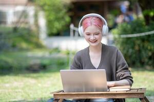 Woman working at the laptop in the backyard with a lot of greenery,  laptop and portrait of woman in park for education photo