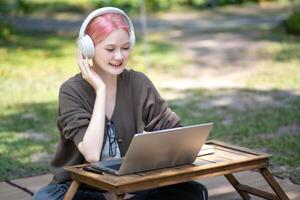 Woman working at the laptop in the backyard with a lot of greenery,  laptop and portrait of woman in park for education photo