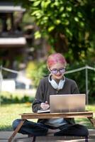 Woman working at the laptop in the backyard with a lot of greenery,  laptop and portrait of woman in park for education photo