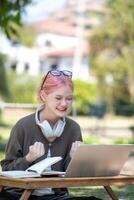 Woman working at the laptop in the backyard with a lot of greenery,  laptop and portrait of woman in park for education photo