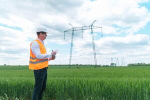 Engineer working near transmission lines. Electrical engineer checks high voltage lines. Transmission towers. Energy efficiency conception photo