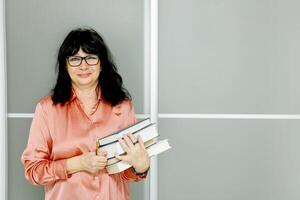 senior woman with a stack of books in her hands photo