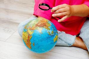 woman looking at a globe through a magnifying glass photo