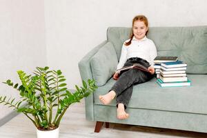 smiling pretty girl on the sofa surrounded by books photo