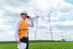 Engineer working near transmission lines. Electrical engineer checks high voltage lines. Transmission towers photo