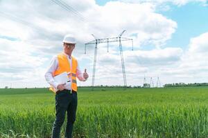 Engineer working near transmission lines. Electrical engineer checks high voltage lines. Transmission towers. Energy efficiency conception photo