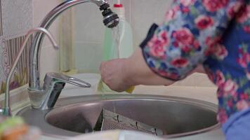 senior Kaukasisch vrouw het wassen gerechten met geel spons Bij keuken video