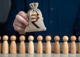 A man holds a indian rupee money bag above the crowd.Salaries. Crowdfunding and fundraising. Social politics. Deposits and loans. Budgetary funds for social policy. photo