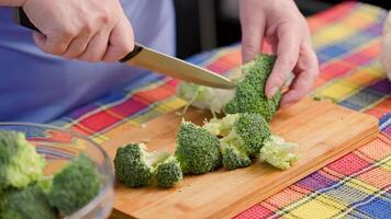 ouderling Kaukasisch vrouw snijdend rauw groen broccoli Aan bamboe snijdend bord video