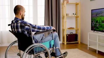 Thoughtful paralyzed man in wheelchair watching tv. video