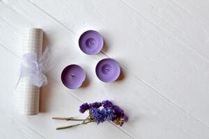 Letter, glasses, candle and flower on the white table. Beutiful female objects on the white wooden background. Flat lay in violet color. photo