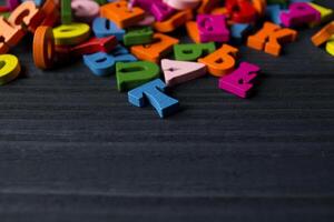 multicolor letras en un oscuro azul de madera antecedentes. vistoso de madera alfabeto en un mesa. foto